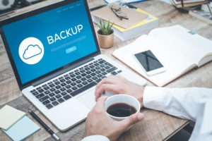 Backups and Data Recovery concept on laptop with business man drinking coffee