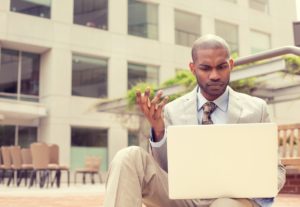 Business man in summer heat on laptop wishing he had a Backup Disaster Recovery (BDR) plan 