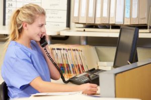 A nurse speaking on the phone in the nurses station to an internal IT help desk 