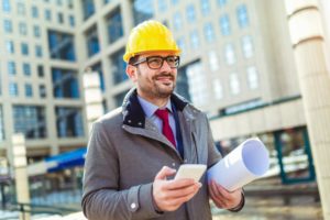 Project manager in a protective helmet using a phone with VOIP Support