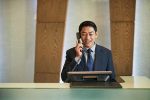 Male receptionist calling an IT help desk in a hotel