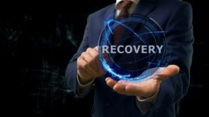 Businessman shows concept hologram Recovery on his hand. Disaster recovery preparation concept