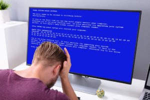 Worried Man At Computer With System Failure Screen At The Workplace Before Contacting the IT Help Desk 