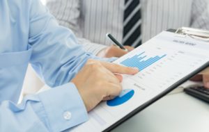Business man pointing to a graph on the IT management reports on a clipboard 