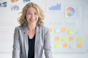 Small business owner, woman in blazer, smiling, working in the IT industy with IT employees 