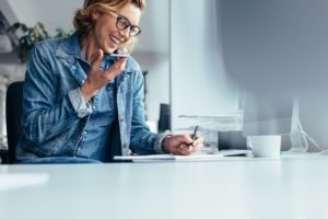 Business woman at her desk, on speaker phone with her managed service provider