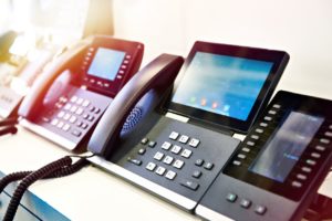 Voice-over-IP (VoIP) phones in a row in an office desk