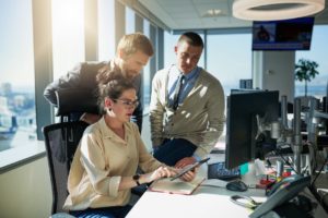 Group of employees in an office using computers with Office 365 to improve office communication and project collaboration