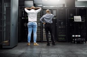 Two IT technicians having difficulty repairing IT system in a server room - a concept of business downtime. 