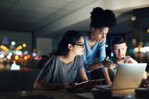 An IT team on-call working on a laptop while dealing with a company's system downtime. 