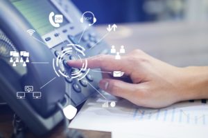 Close-up shot of an employee's hand pressing buttons on its VoIP phone system. 