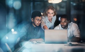 IT professionals looking at a laptop in their office to detect signs of malicious activities - using EventTracker Security tools