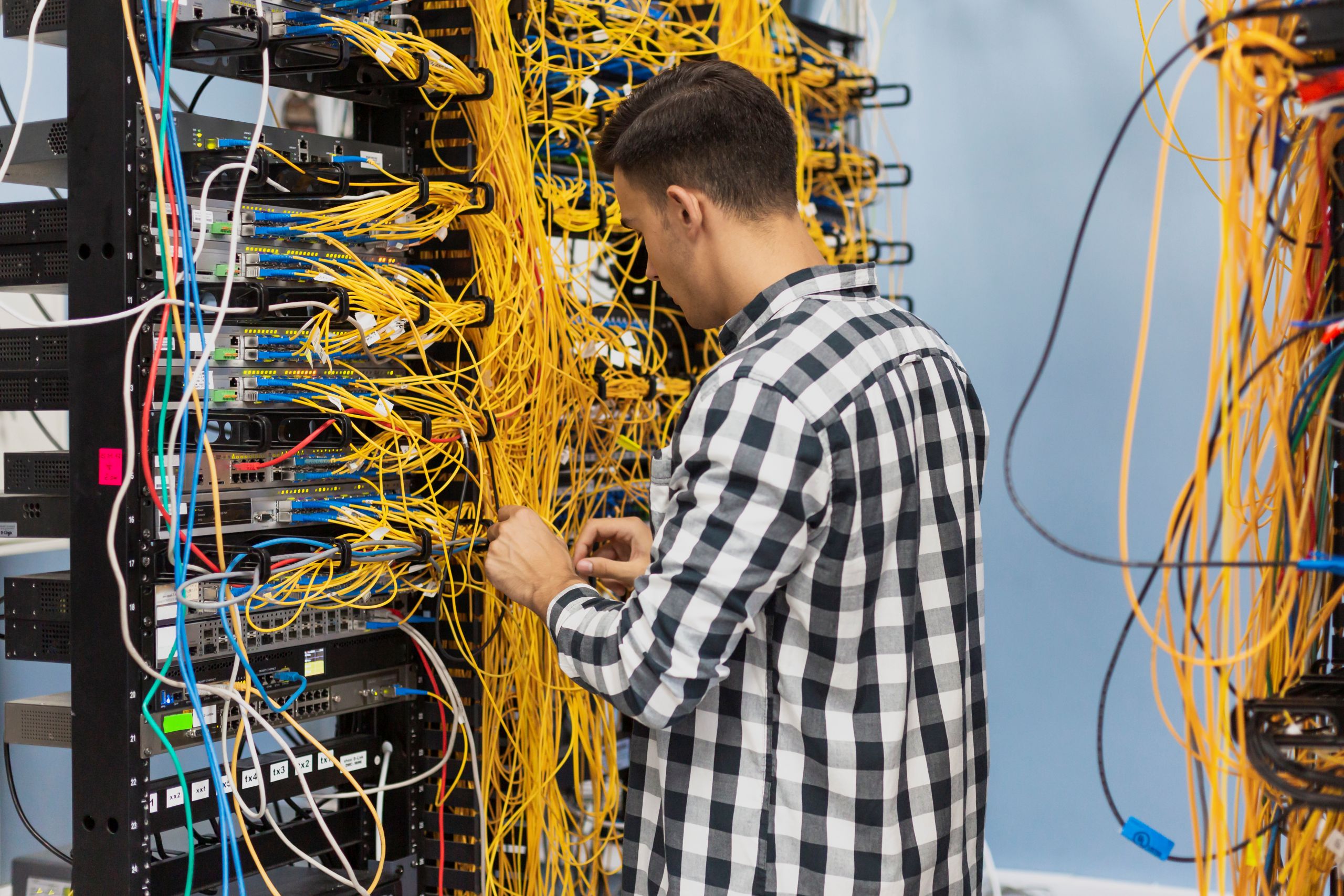 Technician managing tangled yellow cables in server rack