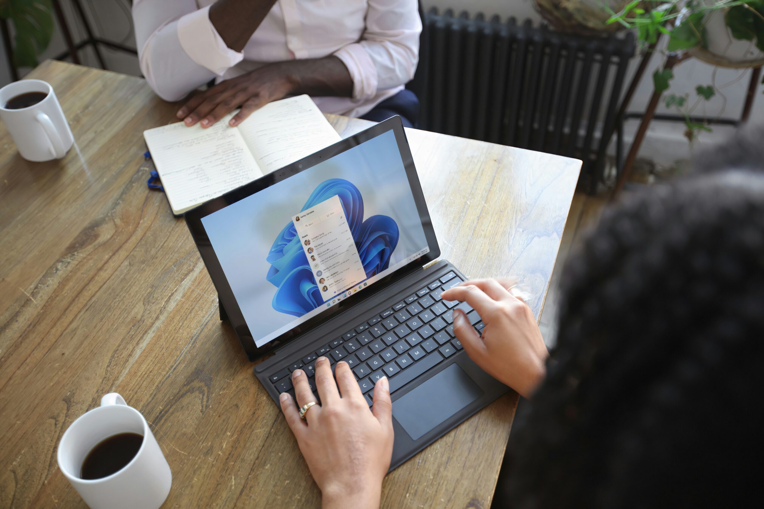 Overhead view of hands typing on a laptop showing Windows UI.